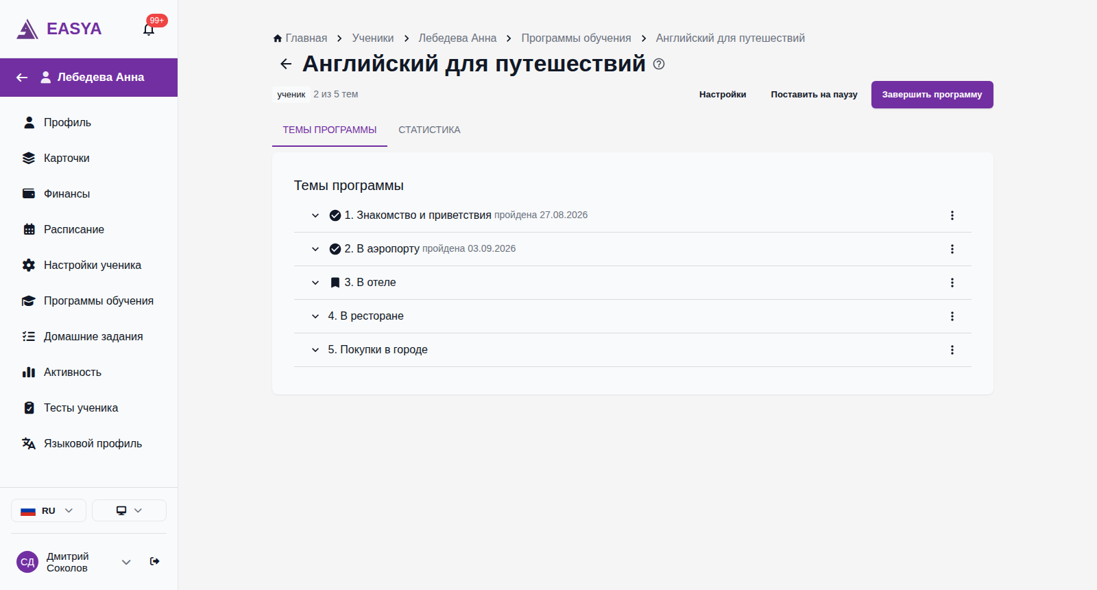 Вкладка «Темы программы» назначенной программы «Английский для путешествий»: у первых двух тем галочка и подписи «пройдена 27.08.2026» и «пройдена 03.09.2026», у третьей темы — закладка «сейчас», справа у каждой темы кнопка меню «три точки».